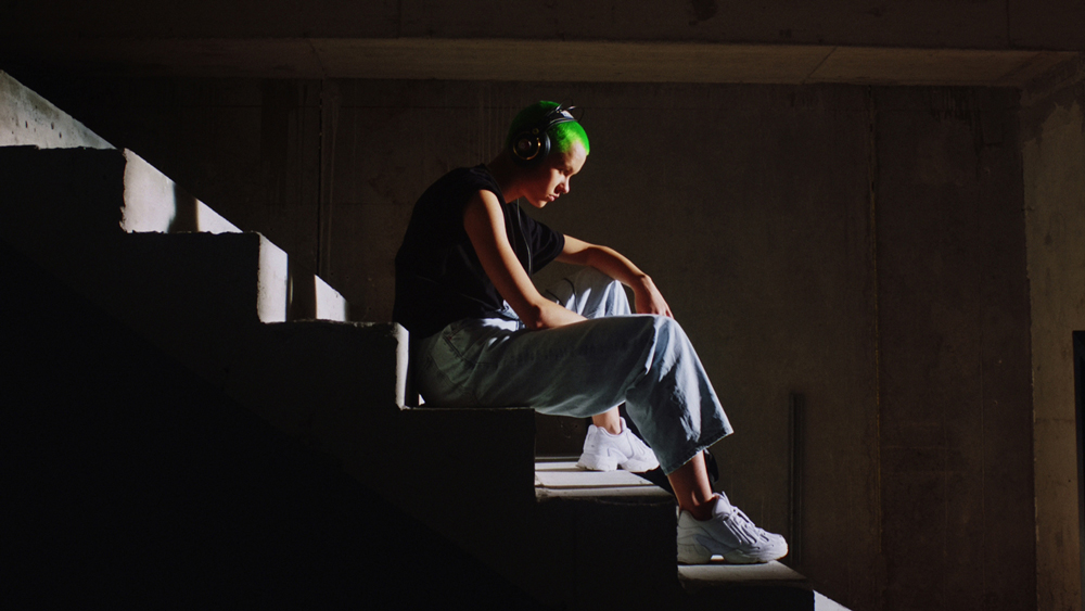 Elina mit Kopfhörern auf einer dunklen Treppe